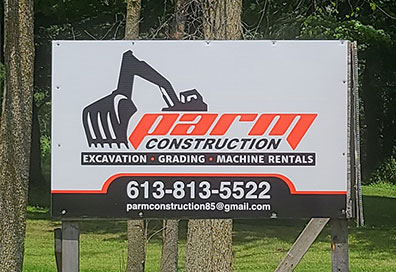 A Parm Construction sign advertising excavation, grading and machine rentals